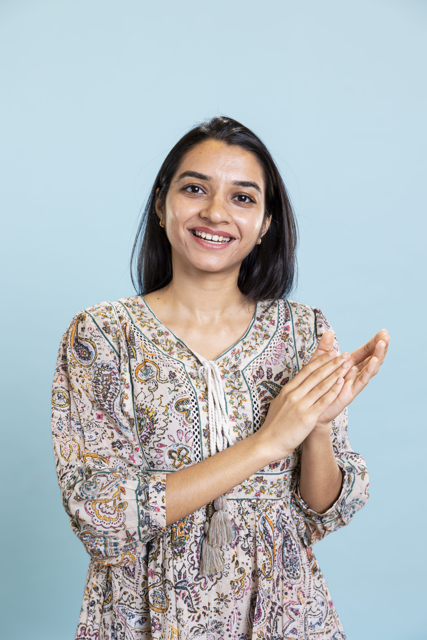 Indian satisfied woman clapping hands and feeling proud of a milestone in studio, pleased and satisfied with an achievement. Smiling adult applauding, saying congratulations for victory.